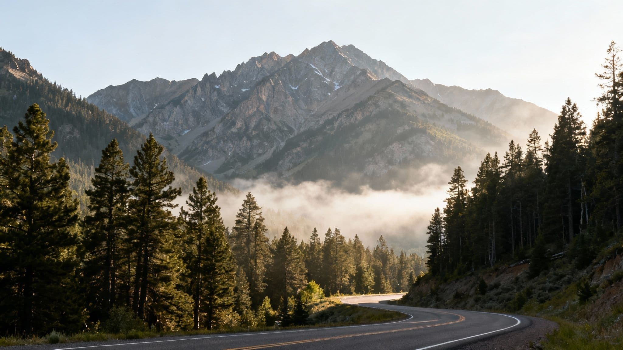 Autumn colors line the winding road of Big Cottonwood Canyon, with mountains in the background.