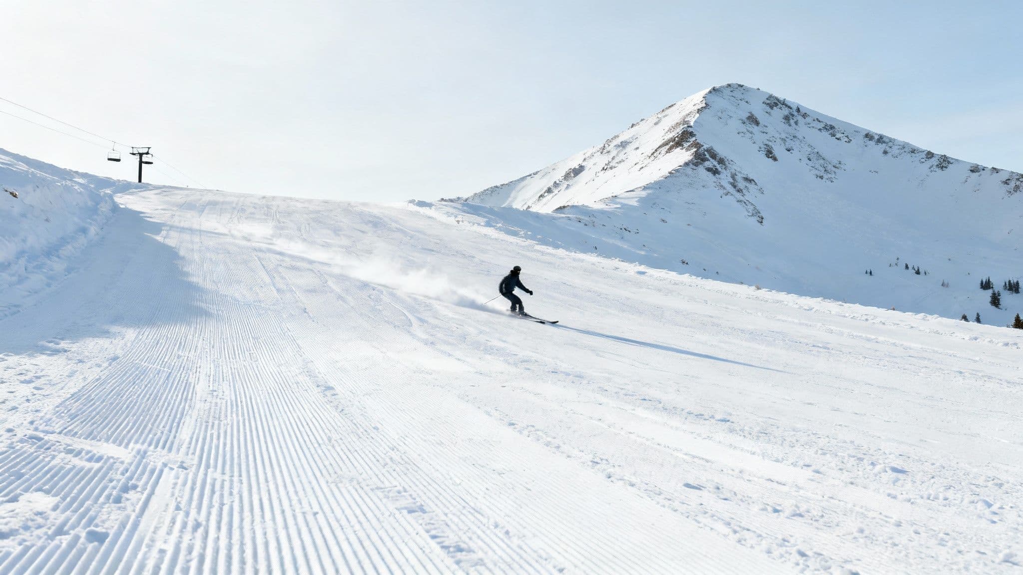 A skier carves through deep powder on a sunny day at a ski resort in Big Cottonwood Canyon.