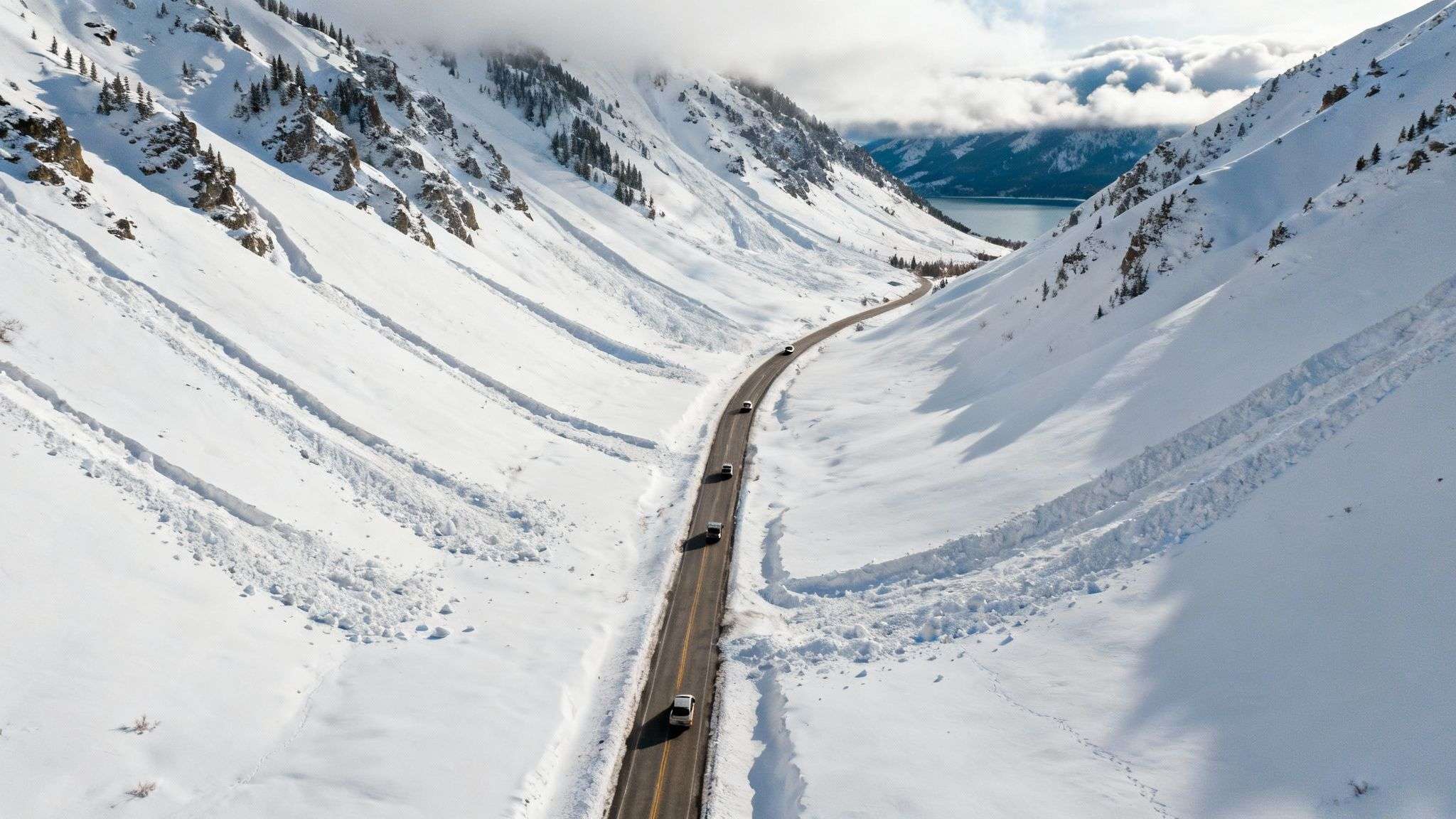 Steep, snow-covered mountains towering over the Little Cottonwood Canyon road. The terrain highlights the high avalanche risk.
