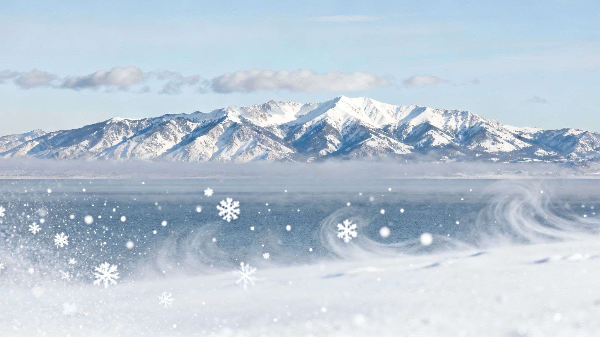 A skier makes fresh tracks in deep powder with snow-covered mountains in the background at Snowbird.