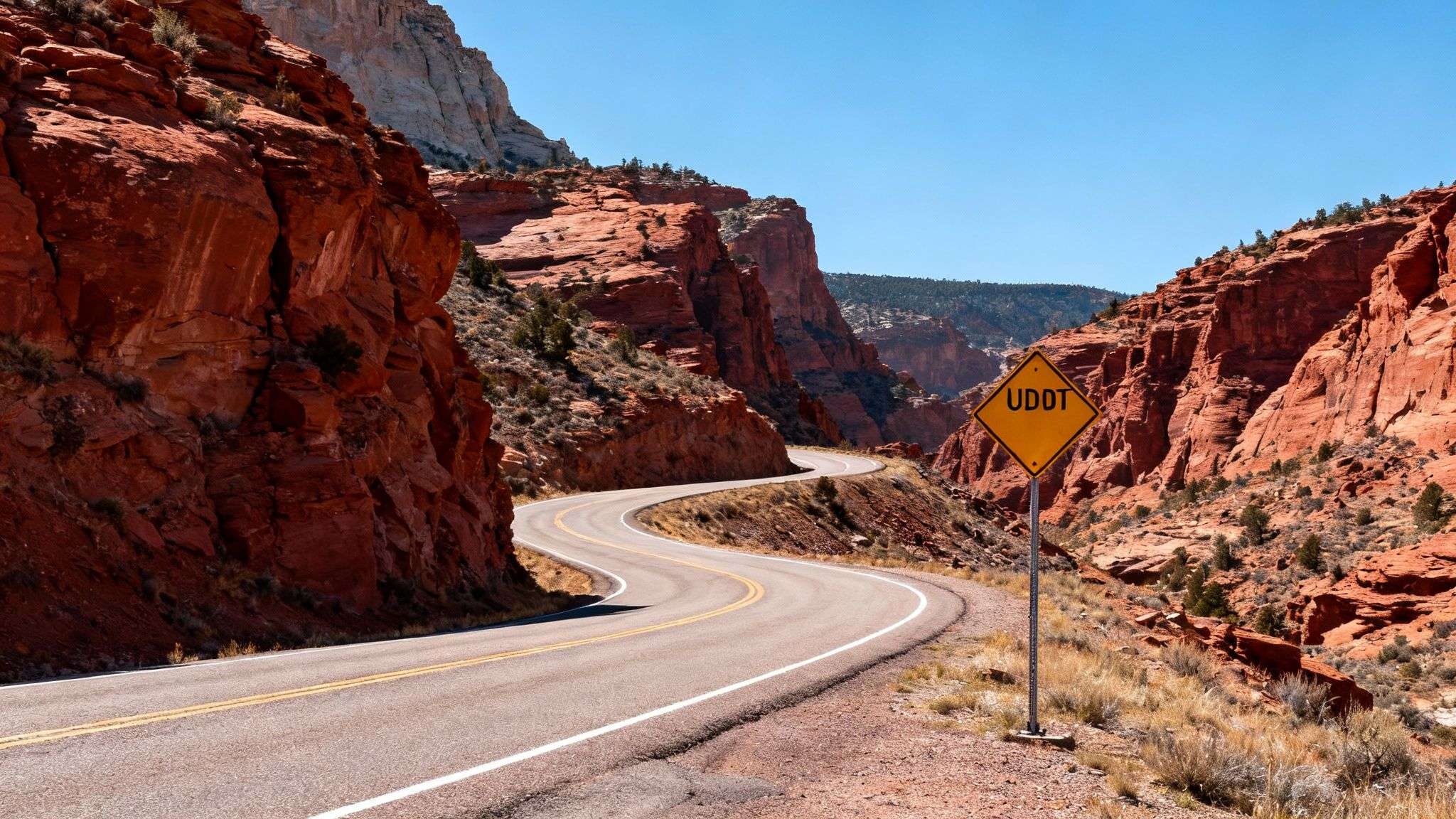 A snowy mountain road in Utah with cars driving cautiously, illustrating the importance of checking road conditions.